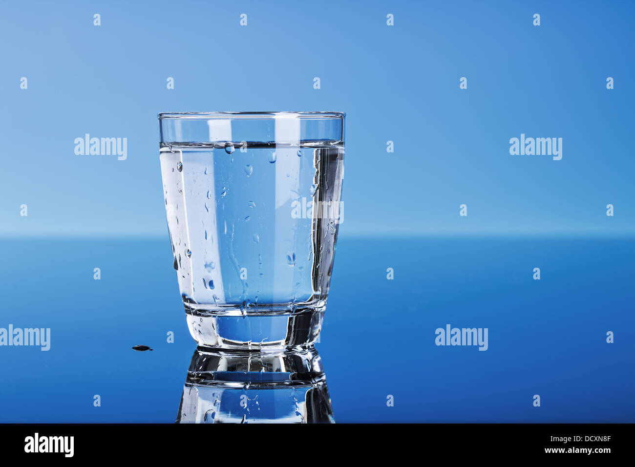 drinking water in a glass on blue Stock Photo