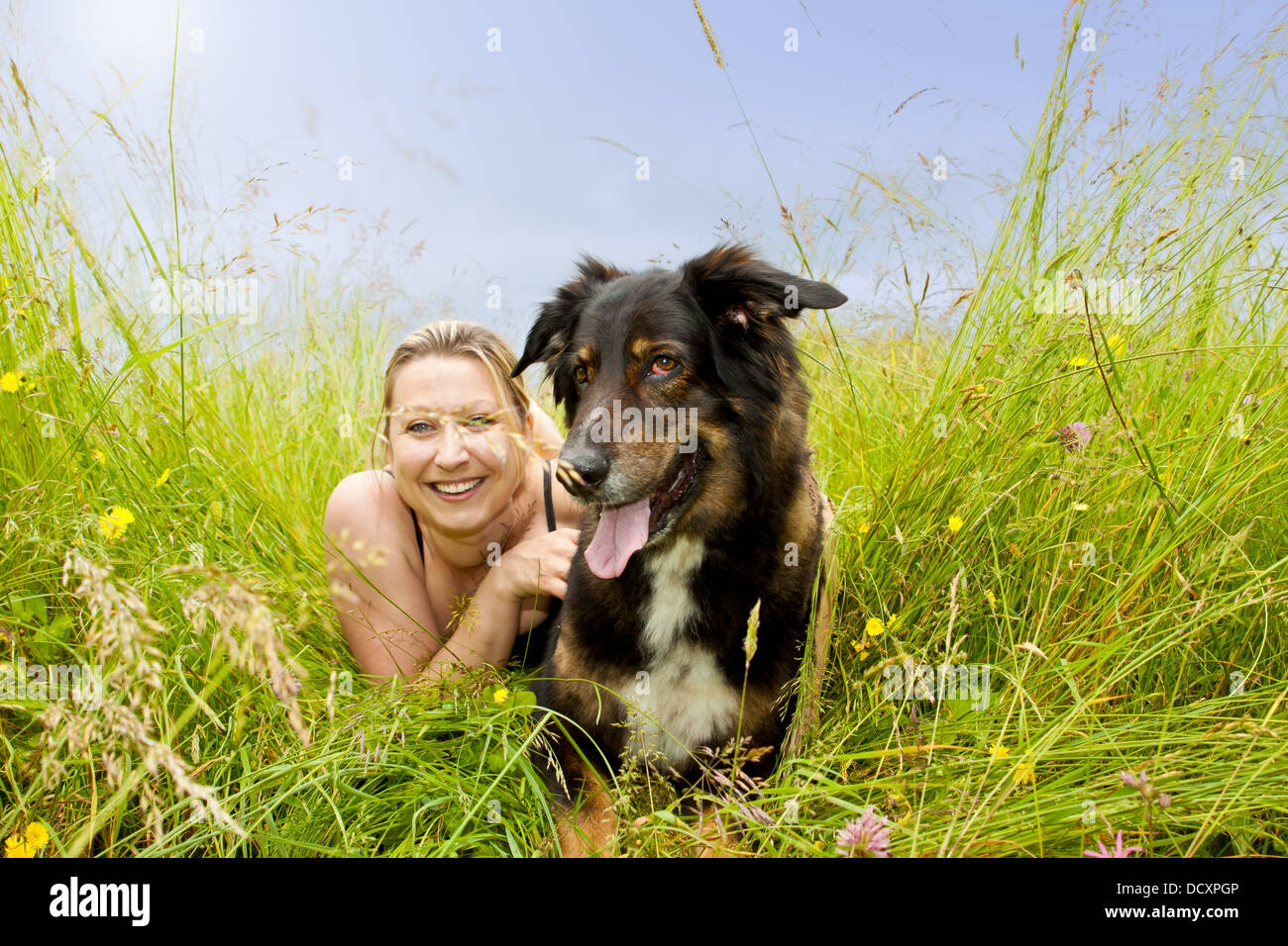 pretty woman with dog is lying on grass Stock Photo