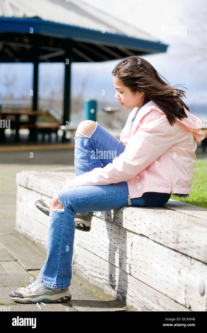 Preteen girl tying shoes outdoors near lake Stock Photo - Alamy