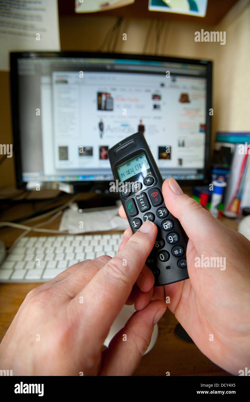 Hand Holding Dialing Phone Handset in front of Computer with Amazon on ...