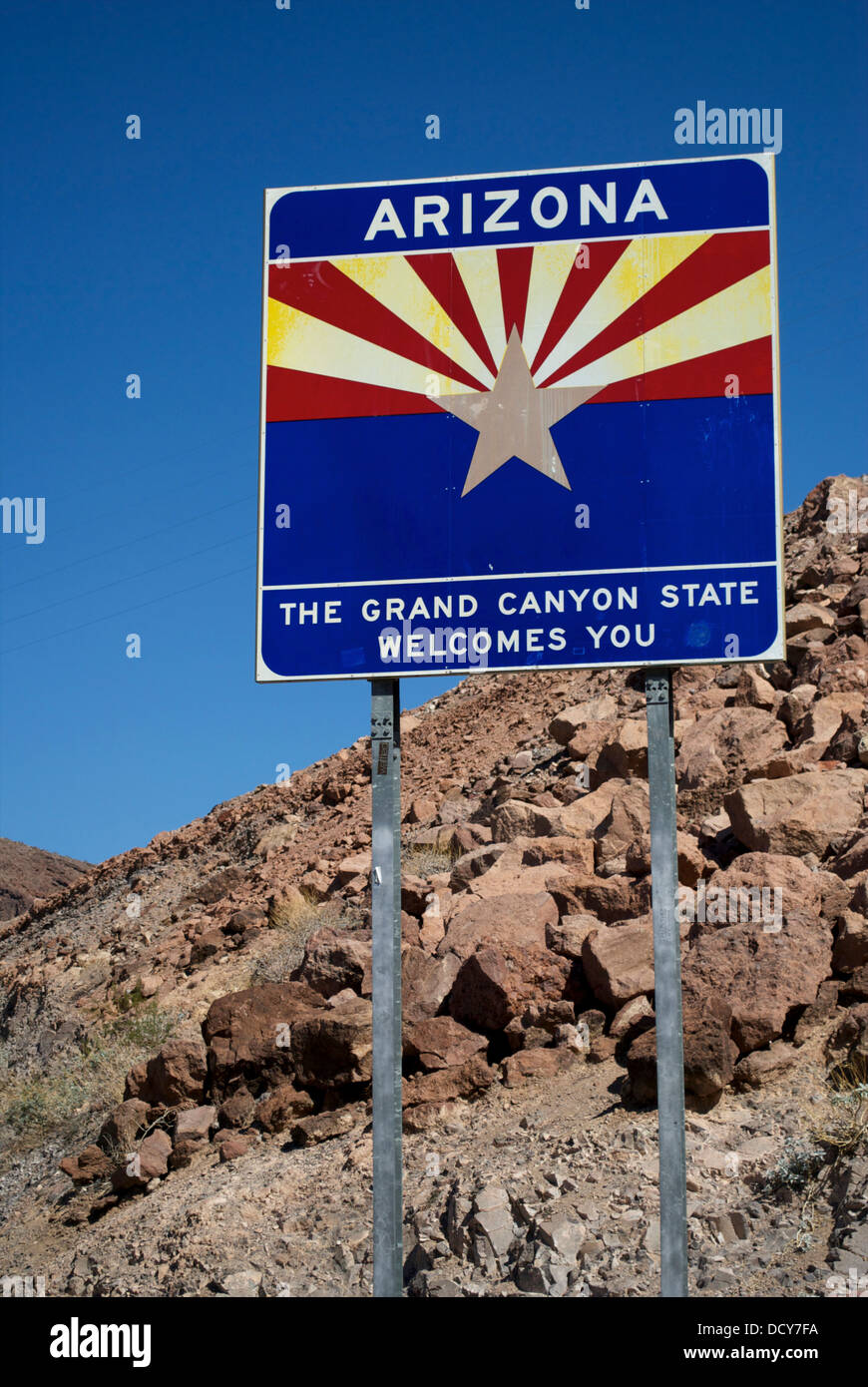 The Arizona State sign at the side of the road near Hoover Dam, rocks and blue sky behind it. Stock Photo