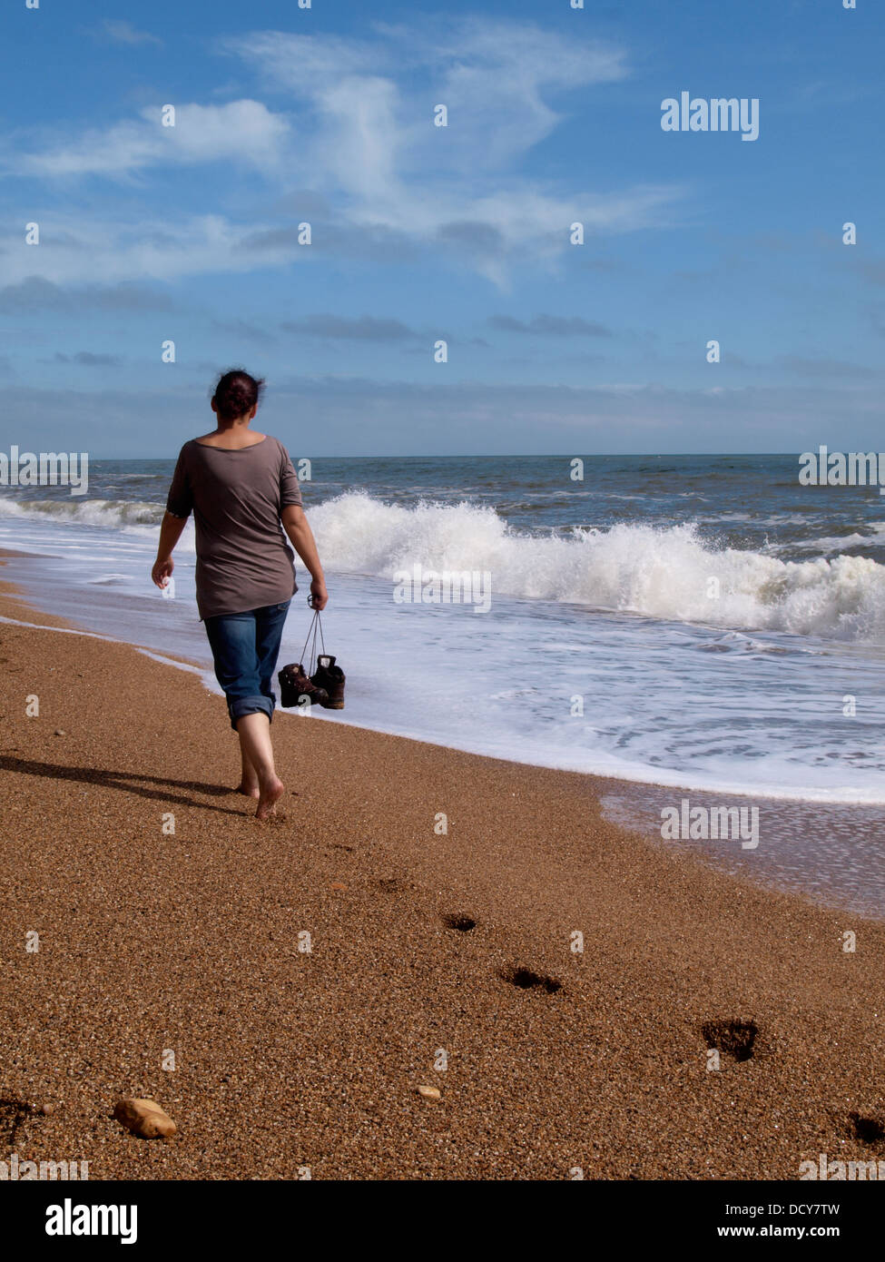 Woman walking along the beach alone, Dorset, UK 2013 Stock Photo