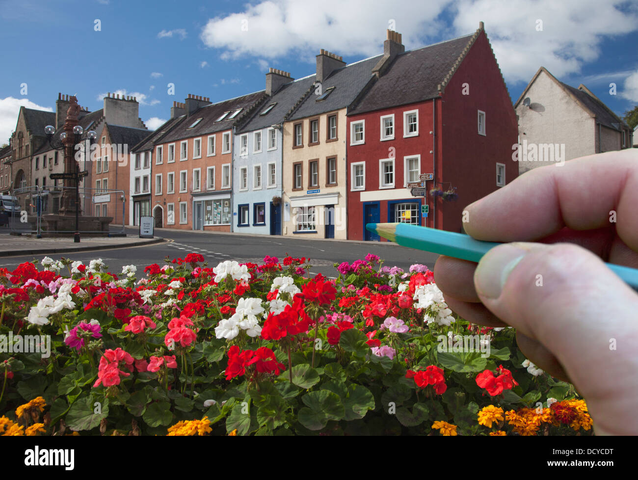 Digitally Enhanced Image Of Hand Holding Pencil Against Town; Jedburgh, Scottish Borders, Scotland Stock Photo