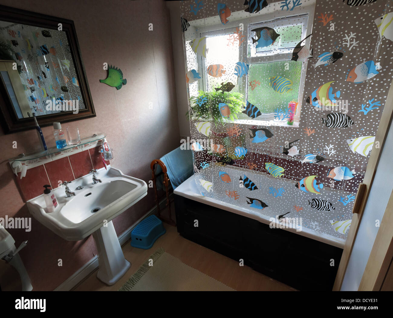 Suburban bathroom with fish shower curtain, bath, pedestal sink wash hand basin Stock Photo