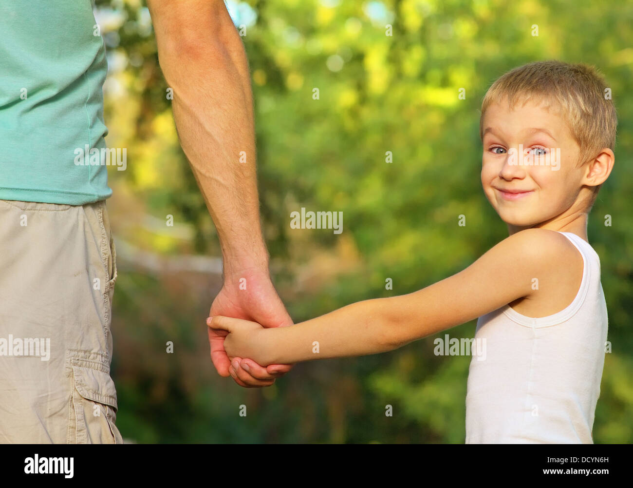 Family Father Man and Son Boy Child holding hand in hand Outdoor Happiness emotion with summer nature on background Stock Photo