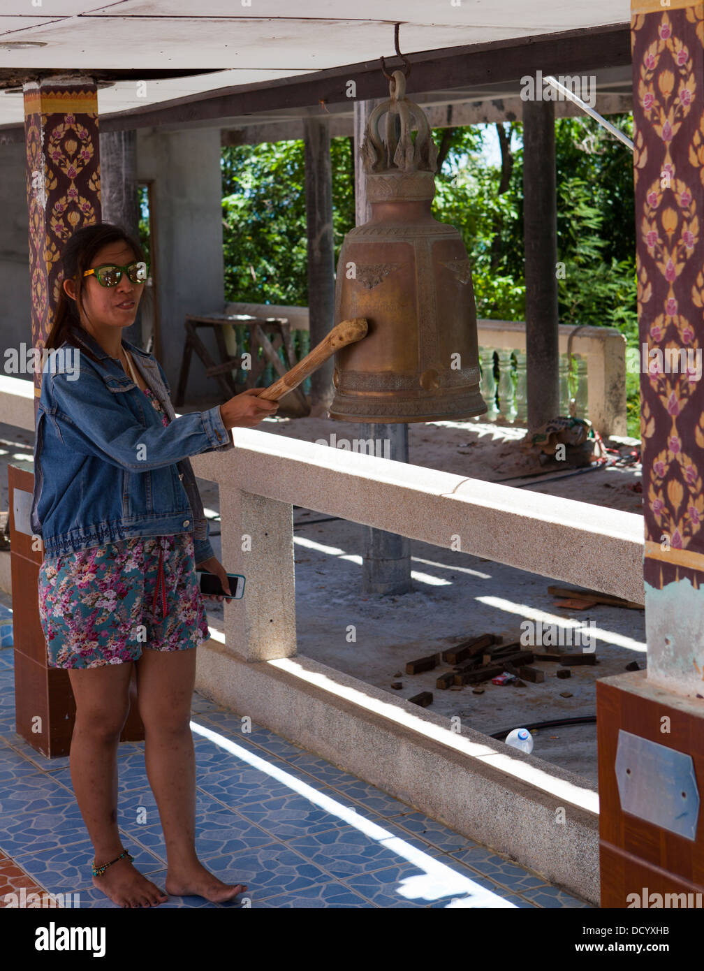 A woman rings a bell at Wat Phra Yai, Temple of the Big Buddha on Ko Samui Island in the Gulf of Thailand. Stock Photo