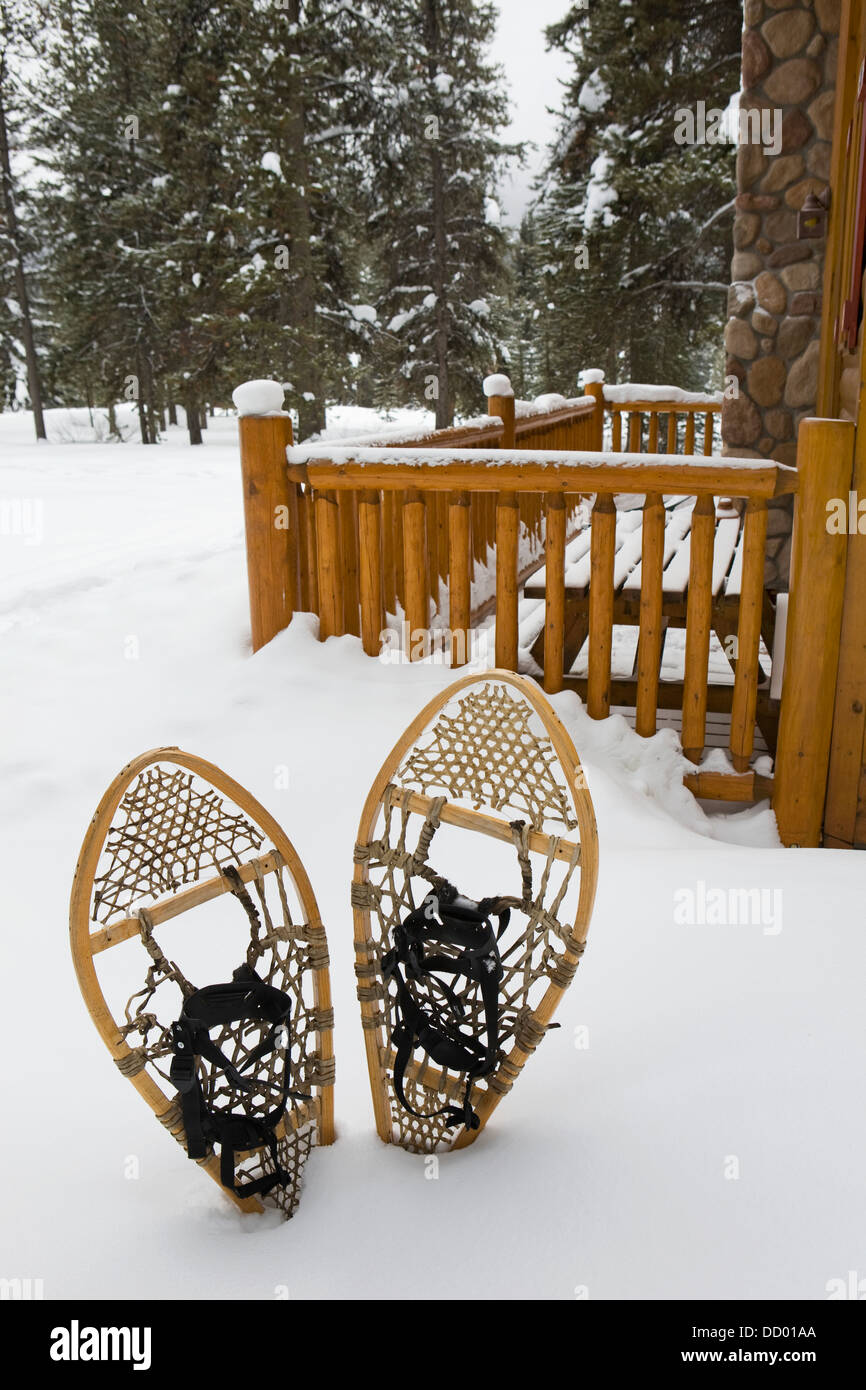Traditional Webbed Snowshoes In The Snow Next To A Log Cabin Patio; Lake Louise, Alberta, Canada Stock Photo