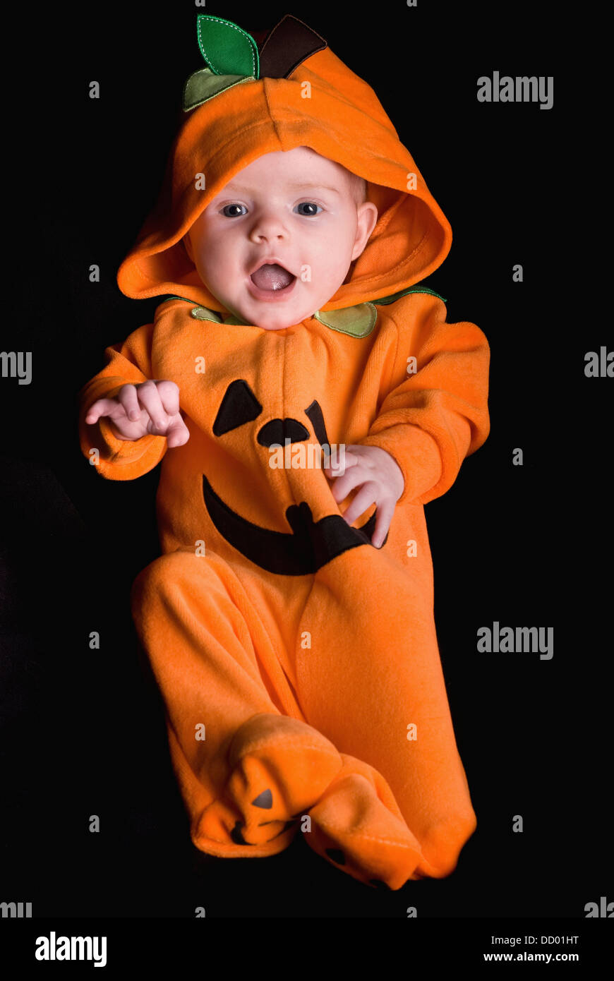 A Baby Wearing An Orange Pumpkin Costume; Alberta, Canada Stock Photo
