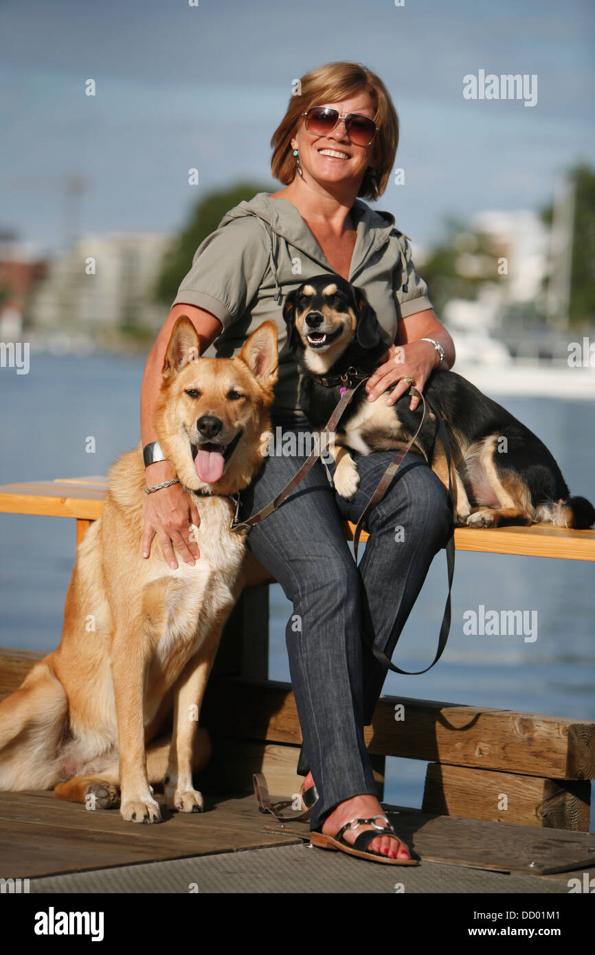 A Woman Sits With And Holds Her Pet Dogs In Victoria's Inner Harbour