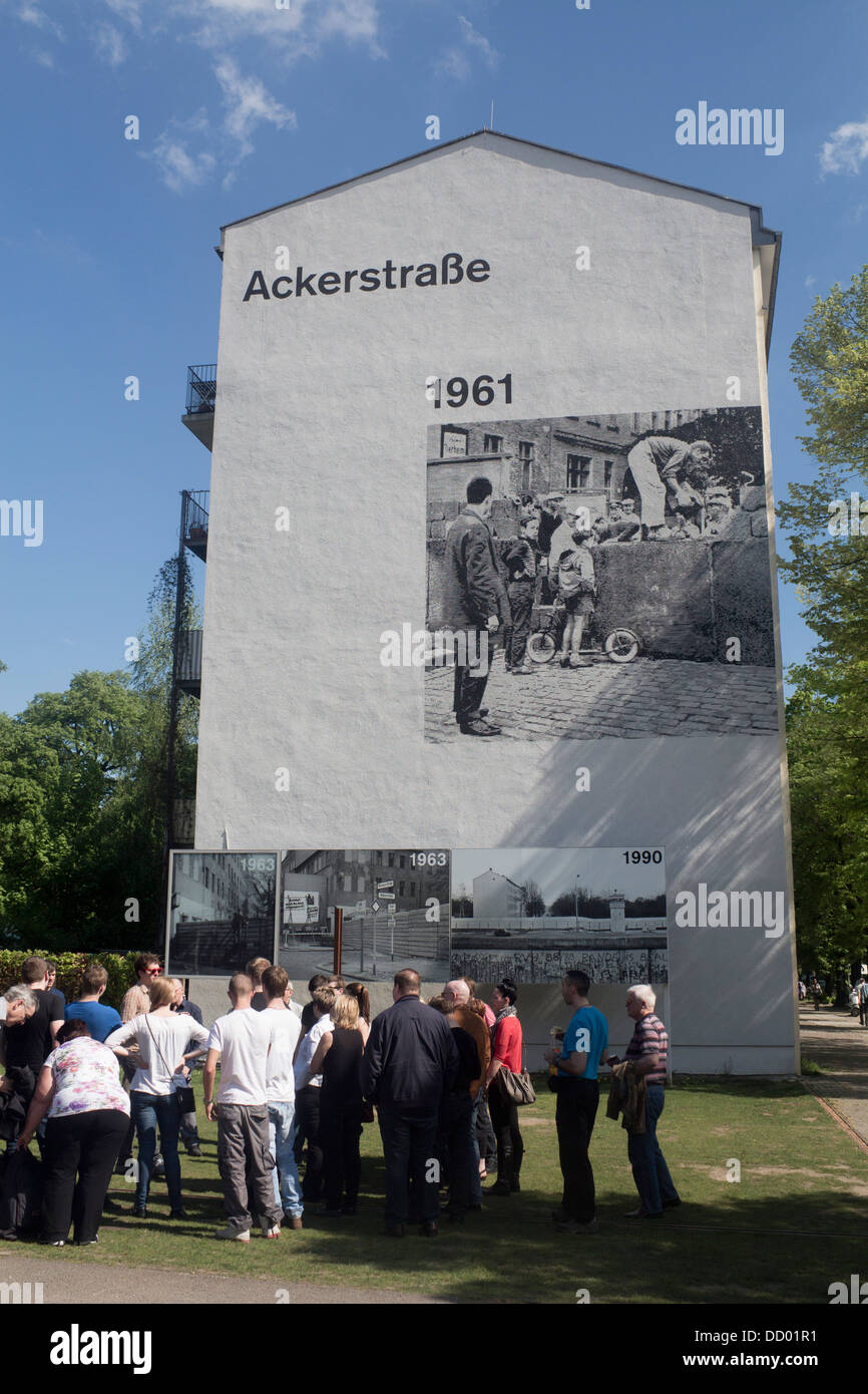 Guided tour group and guide below mural on building at Berlin Wall Memorial Bernauer Strasse Berlin Germany Stock Photo