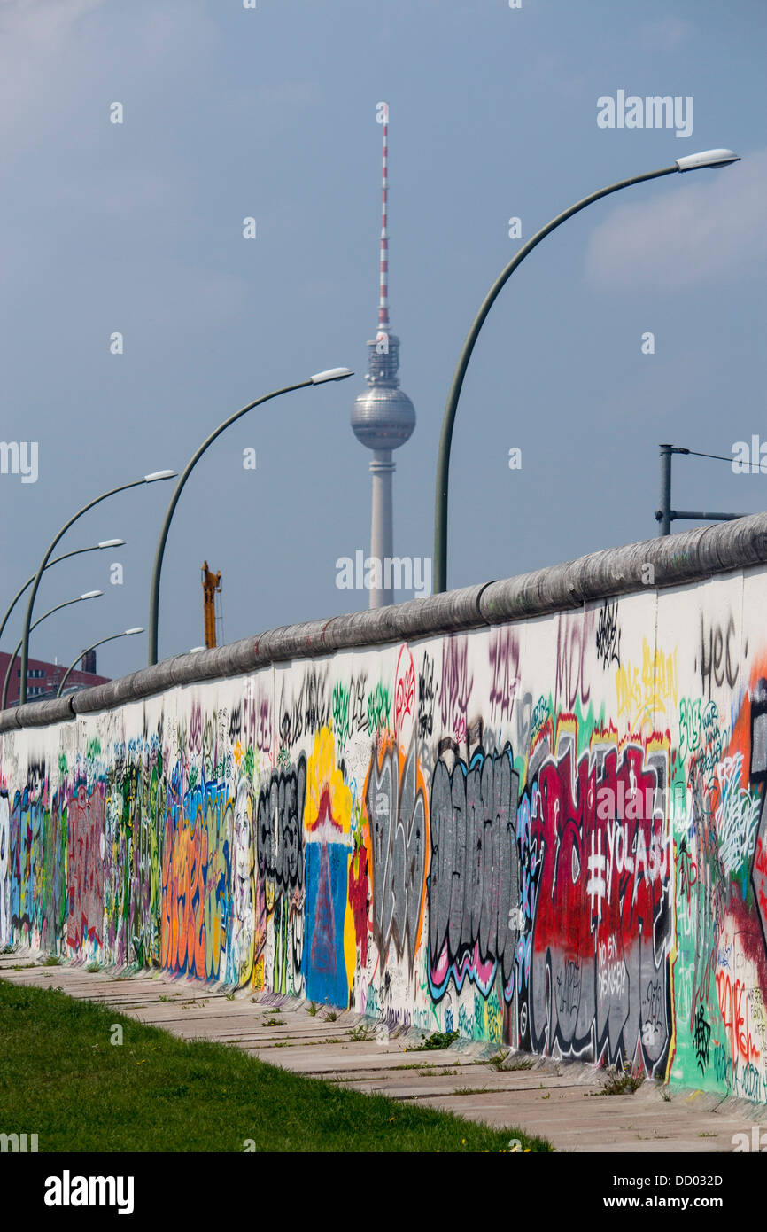 Section of Berlin Wall with graffiti and Fernsehturm TV Tower in distance Berlin Germany Stock Photo