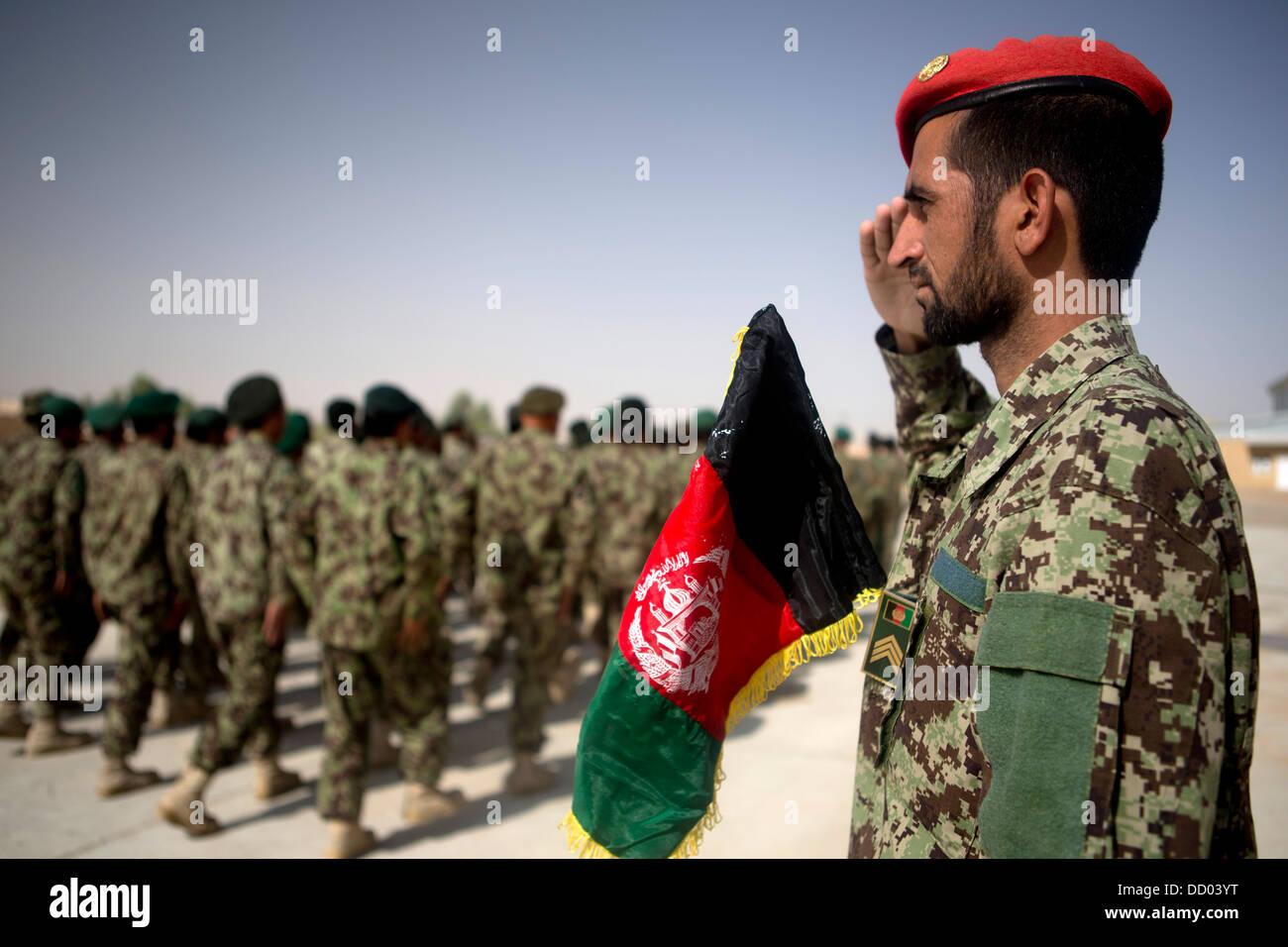 An Afghan National Army officer with the 215th Corps salutes passing troops during a ceremony commemorating the 94th anniversary of Afghanistan's independence from Britain August 19, 2013 at Camp Shorabak, Helmand province, Afghanistan. Stock Photo