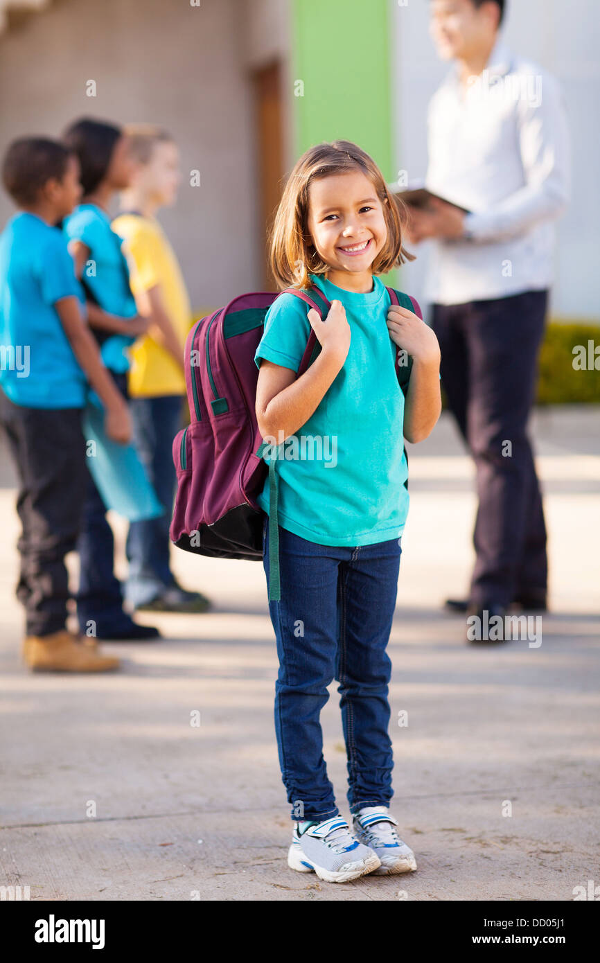 happy primary school student carrying backpack with classmates and teacher on background Stock Photo