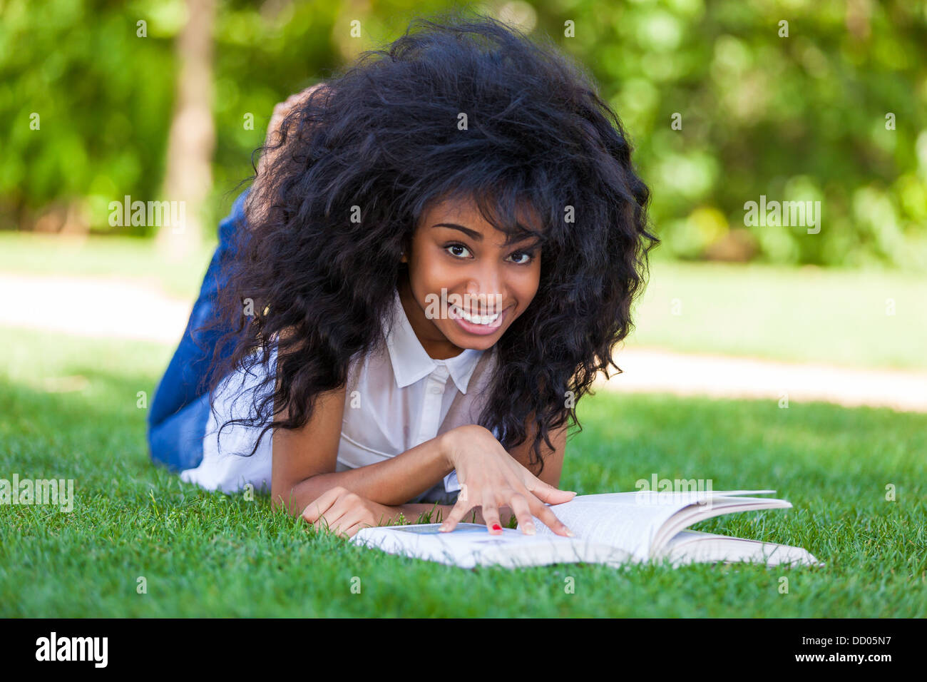 Young student girl reading a book in the school park - African people Stock Photo
