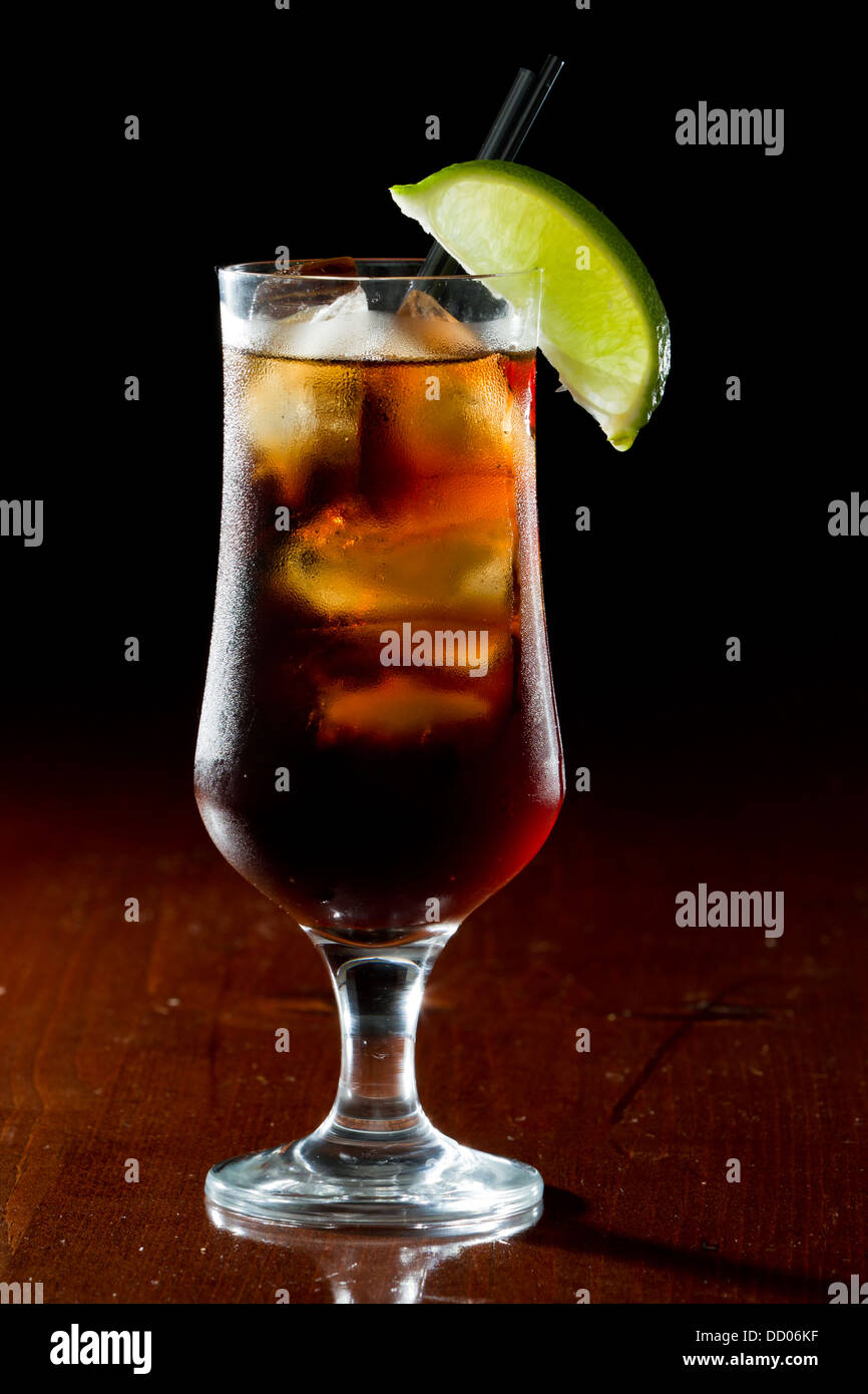 cuba libre, rum and cola cocktail served in a stem glass with a lime