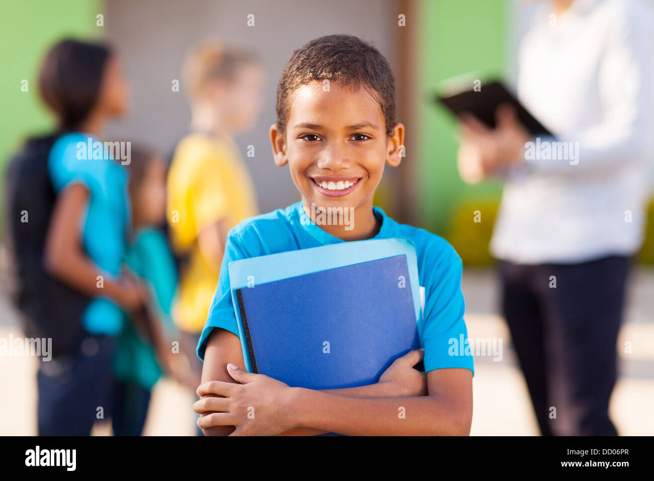 cheerful african male elementary school student holding text books Stock Photo