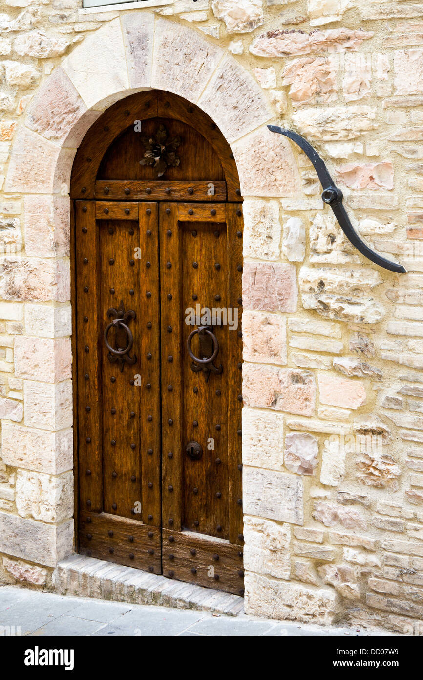 View of old double wooden arched door of stone medieval palace, with traditional iron tie-rod beside, Assisi, Umbria, Italy Stock Photo
