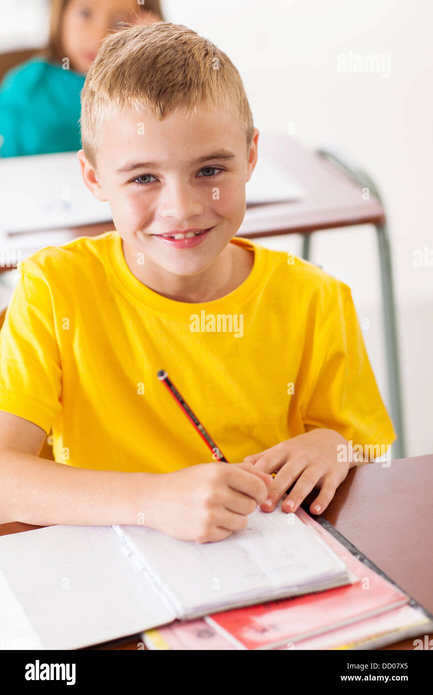 adorable elementary student in classroom writing classwork Stock Photo