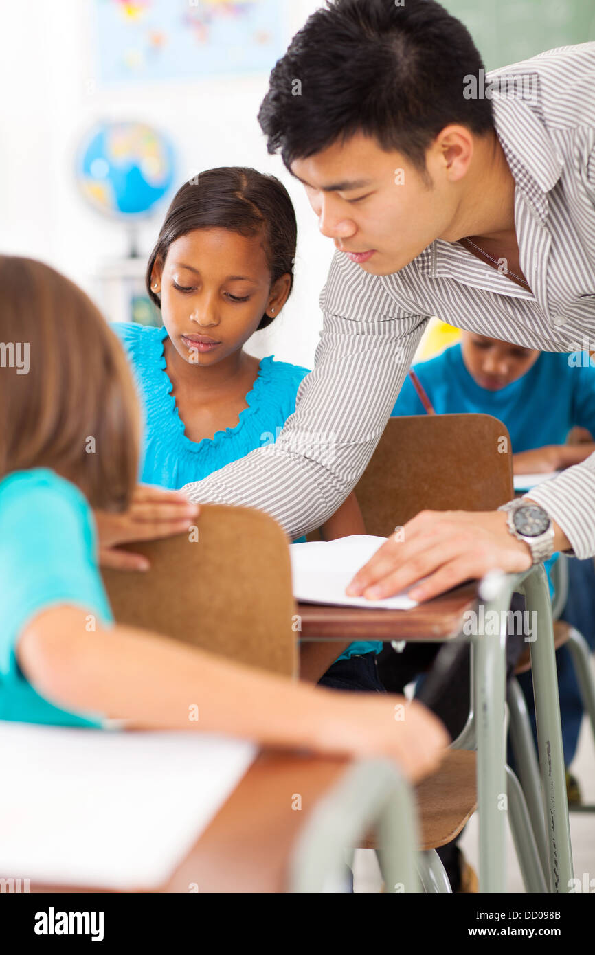 caring primary educator helping a student in classroom Stock Photo