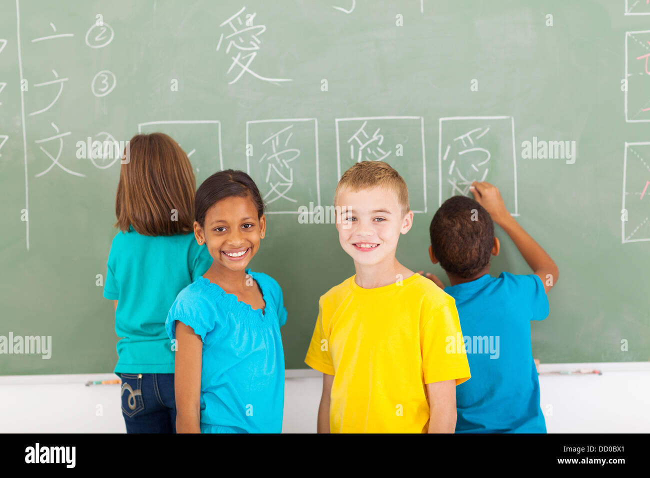 cheerful elementary school students after writing chines on chalkboard Stock Photo