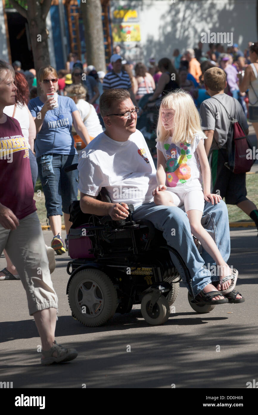 father-ridding-motorized-wheelchair-with-daughter-riding-on-his-lap
