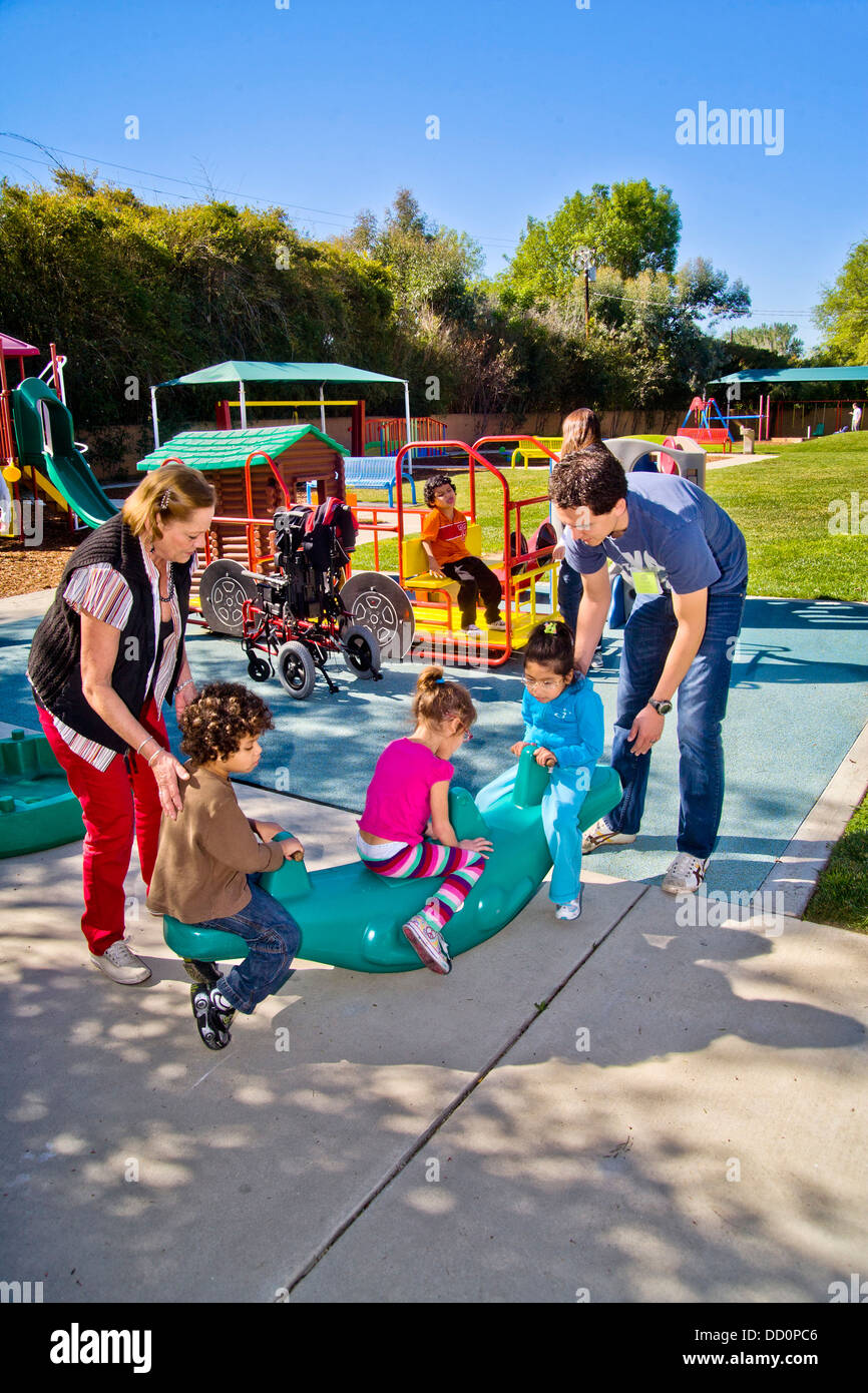 Young and old staff members help blind and crippled children use the playground at the Blind Childrens Learning Center Stock Photo