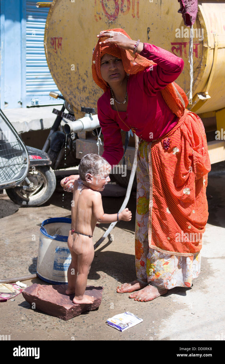 Mother washing baby in the street, Jodhpur, Rajashtan, India Stock Photo