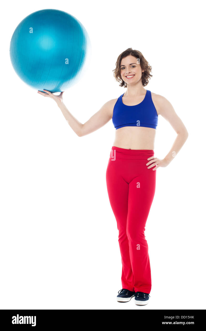 Cheerful gym instructor striking a lovely pose with a big ball in hand