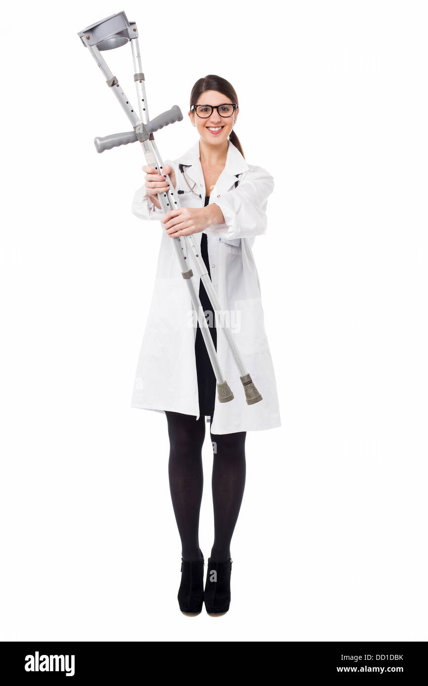 Smiling female doctor displaying a set of crutches Stock Photo