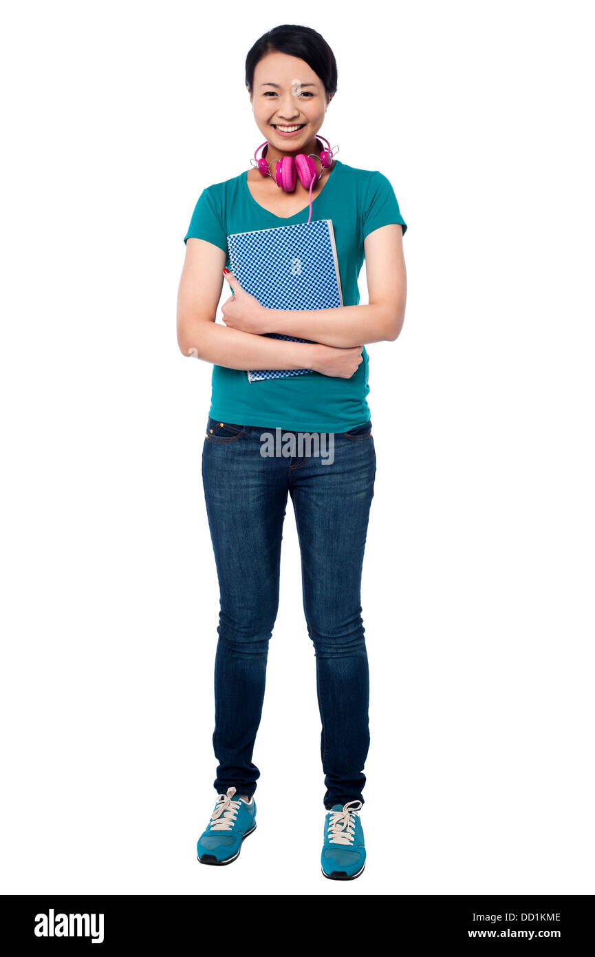Student holding notebook. Pink headphones around her neck. Stock Photo
