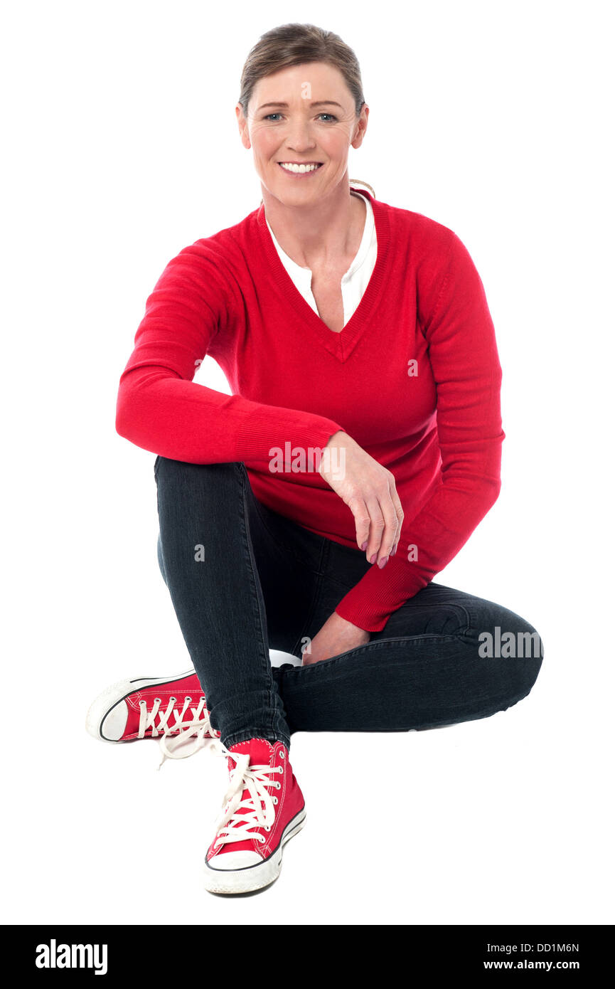 Relaxed trendy lady seated on the floor, studio shot. Stock Photo