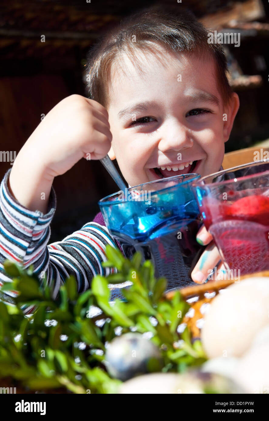 Happy boy colouring easter eggs Stock Photo