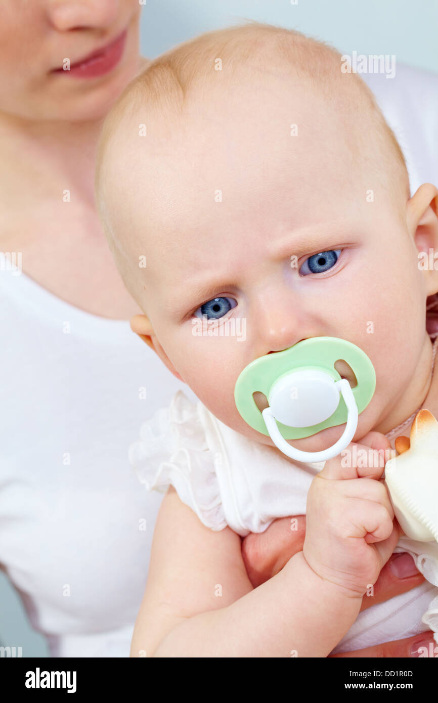 Portrait of cute child with pacifier in mouth held by her mother Stock Photo Alamy