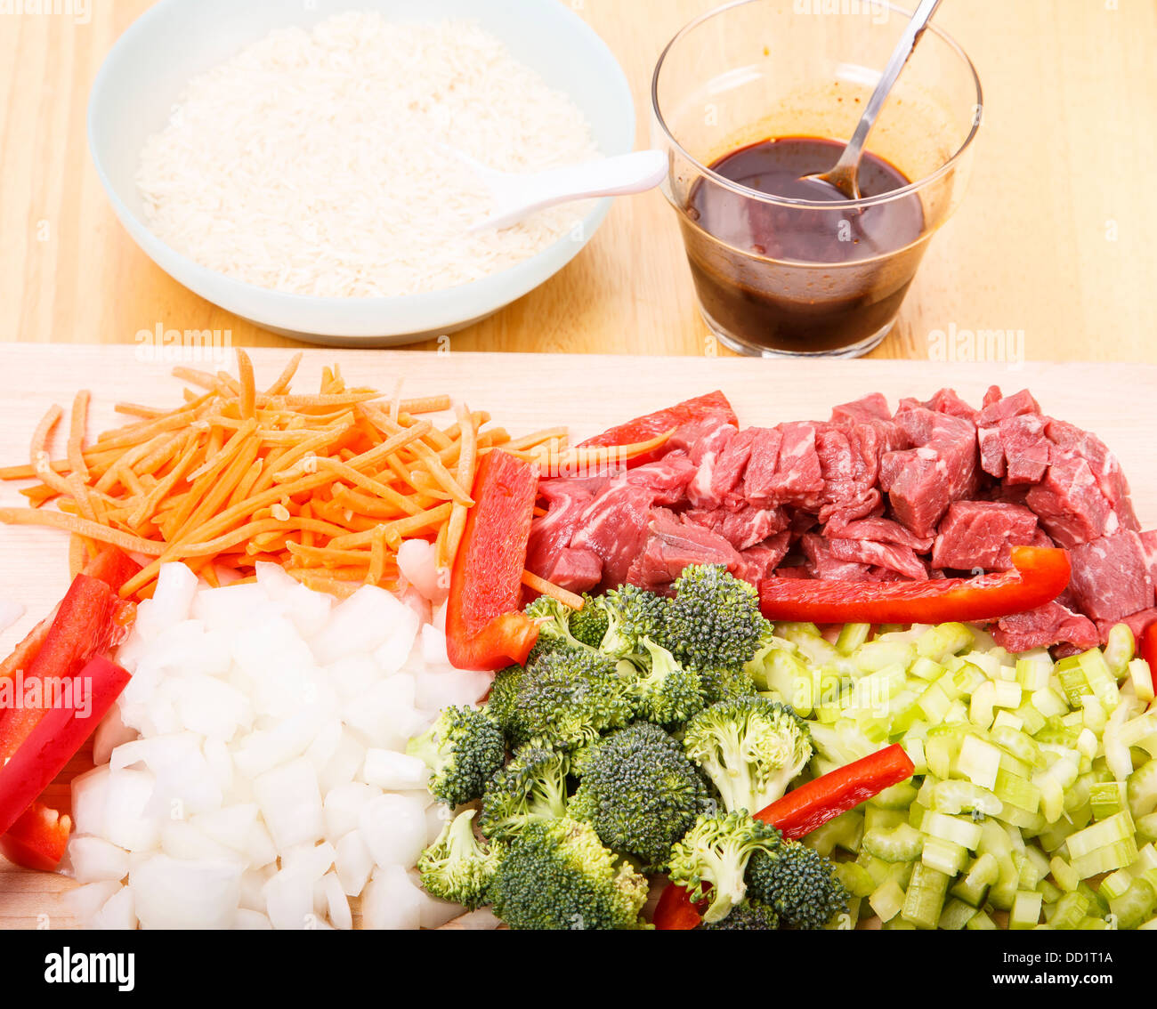 Beef stirfry ingredients on cutting board with rice and soy sauce in