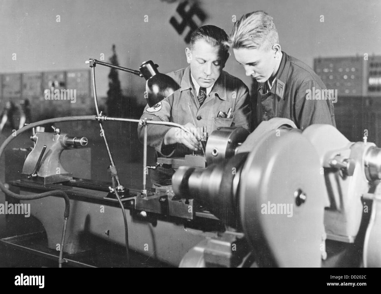 An apprentice of Ernst Heinkel Flugzeugwerke (Ernst Heinkel Aircraft Manufacturer) is pictured with a teacher during the production of aircraft parts between 1937-1943. Place unknown. The Ernst Heinkel Flugzeugwerke was one of the leading defense industry manufacturer in the Third Reich. Photo: Berliner Verlag/Archiv Stock Photo