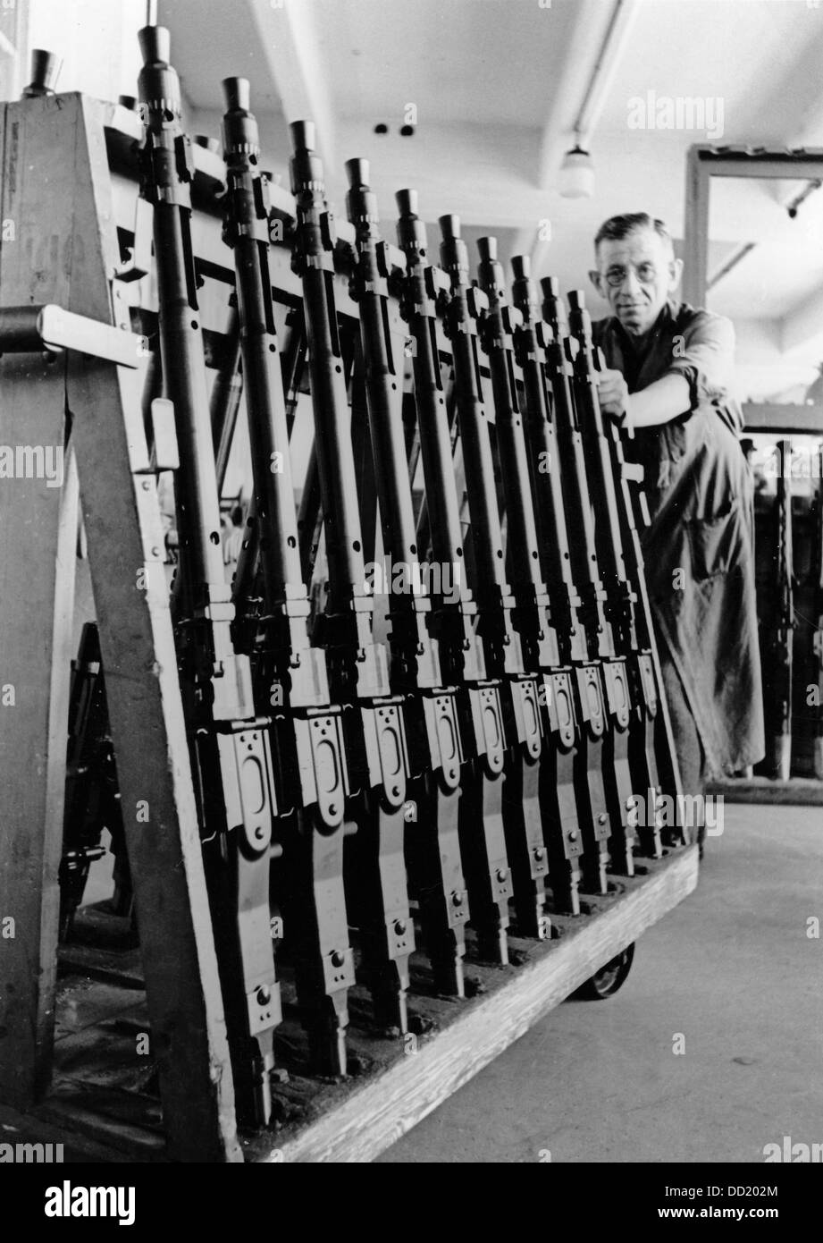 A worker in a machine gun factory carts antitank rifles for final assemblage in September 1943, place unknown. The Nazi Propaganda! on the back of the picture is dated 29 September 1943: 'Successful attrition warfare in the factory. Inventive talent and craftmanship produce more and better weapons. An interesting tour in the machine gun factory. Our image shows: And again, a transport wagon with antitank rifles proceeds towards completion.' Fotoarchiv für Zeitgeschichte Stock Photo