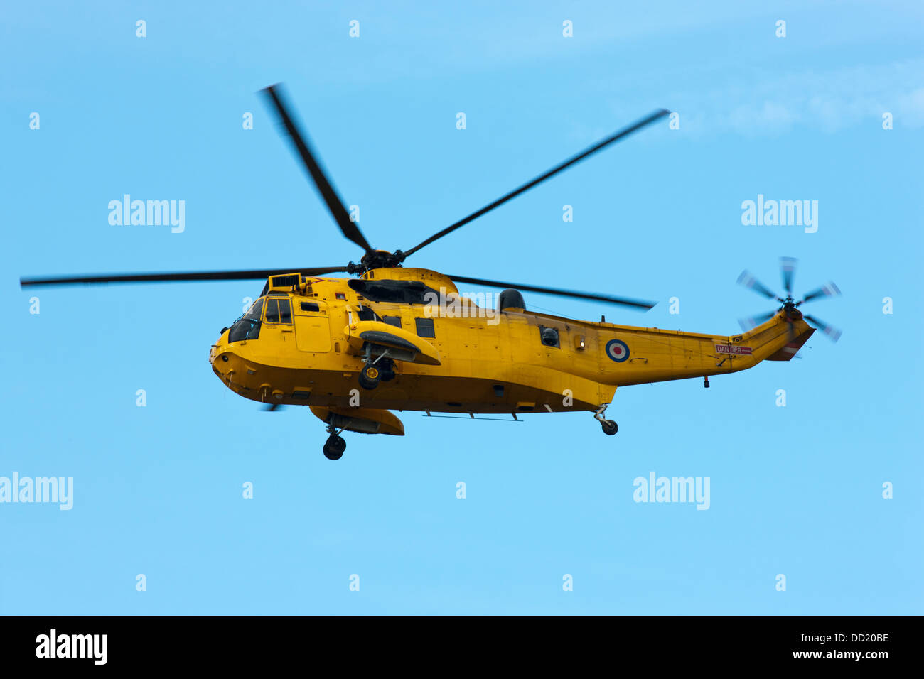 A Yellow Helicopter Flying In A Blue Sky; Northumberland, England Stock