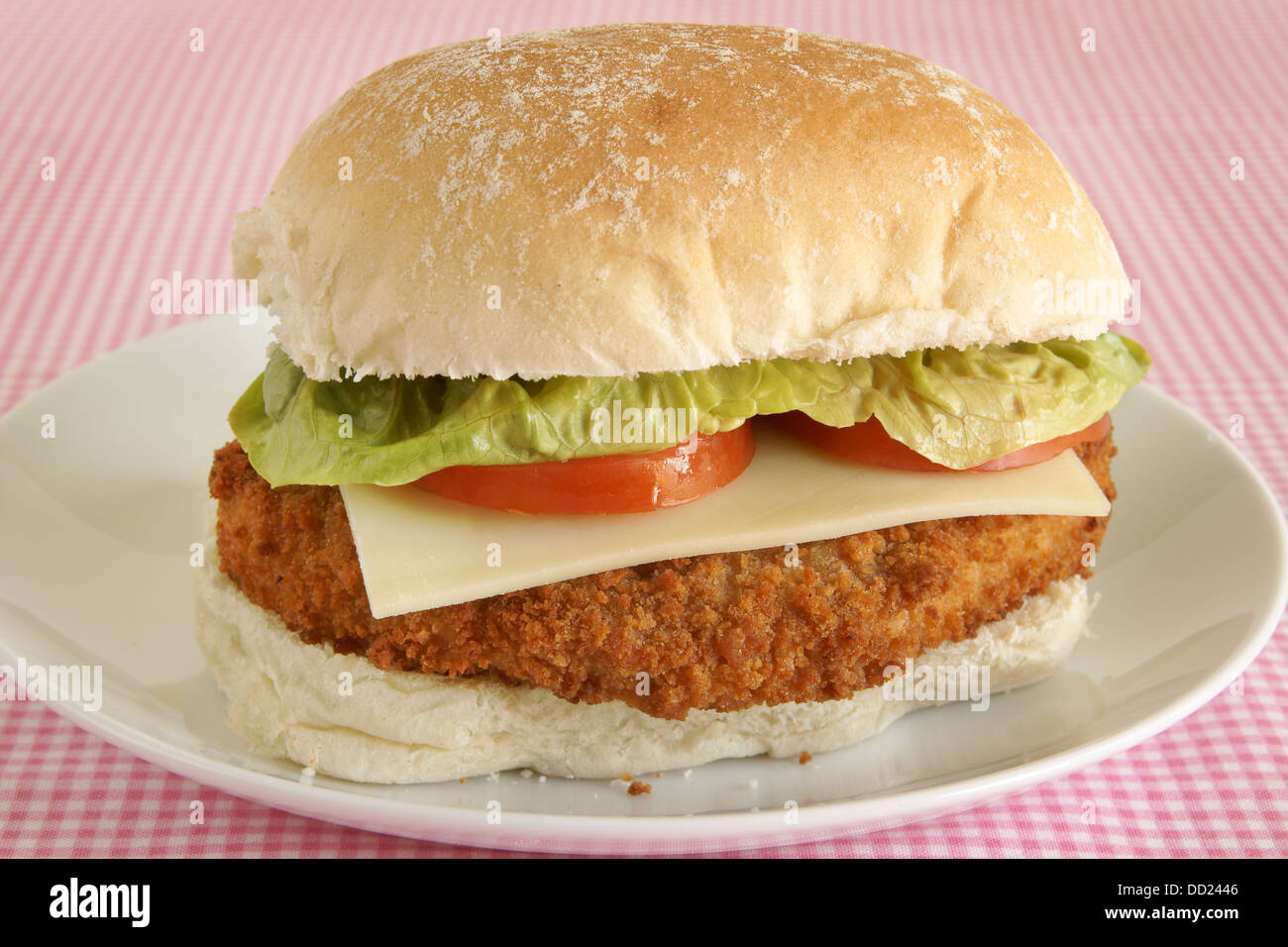 Chicken fillet burger in bread crumbs with cheese lettuce and tomato on