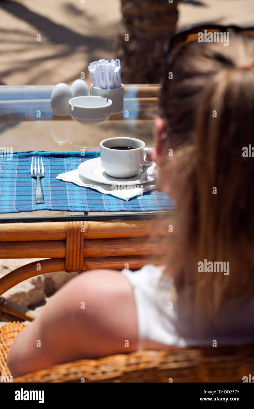 Shallow focus image of a woman enjoying coffee on a beach Stock Photo