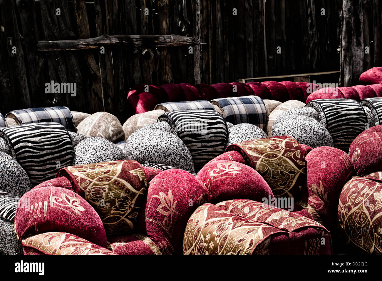 Outdoor furniture shop in Nakuru town: detail of brightly coloured red ,and black and white sofas against wooden fence backdop, Stock Photo