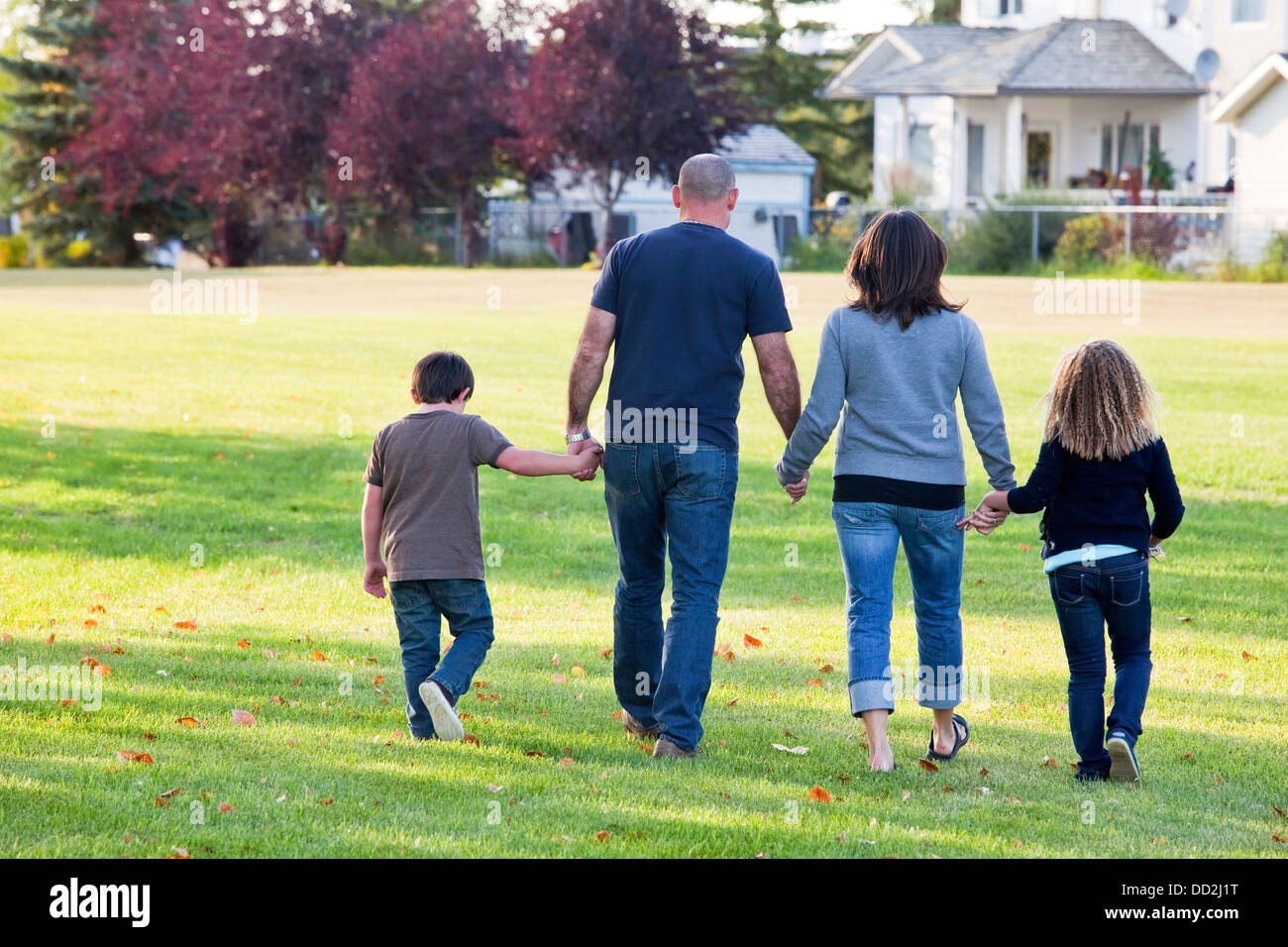 Family Walking Together In A Park; Beaumont, Alberta, Canada Stock Photo