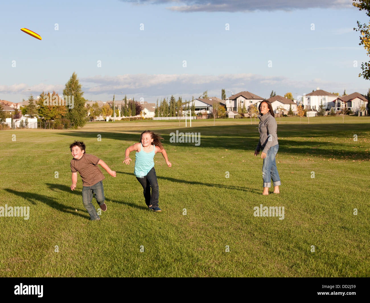 Mother Throwing Flying Disc To Children In A Park; Beaumont, Alberta, Canada Stock Photo