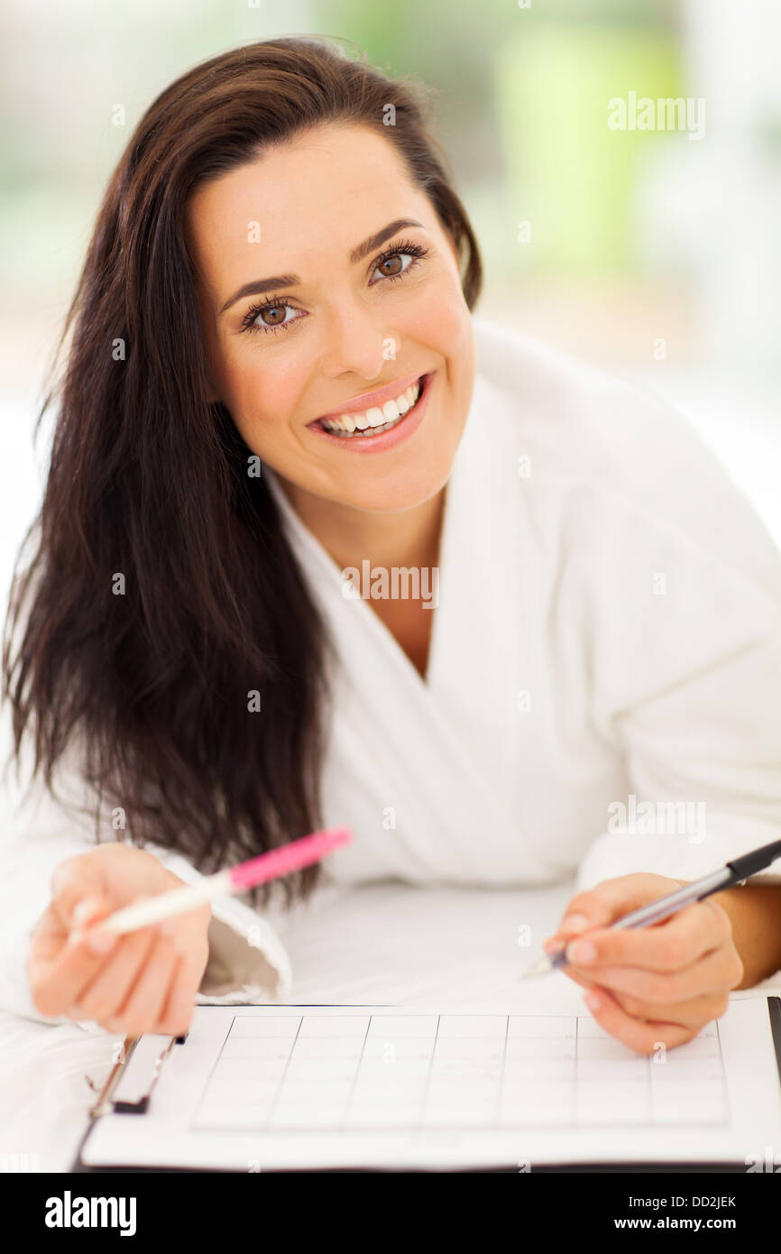 Cheerful woman lying on bed writing on a calendar her pregnancy result