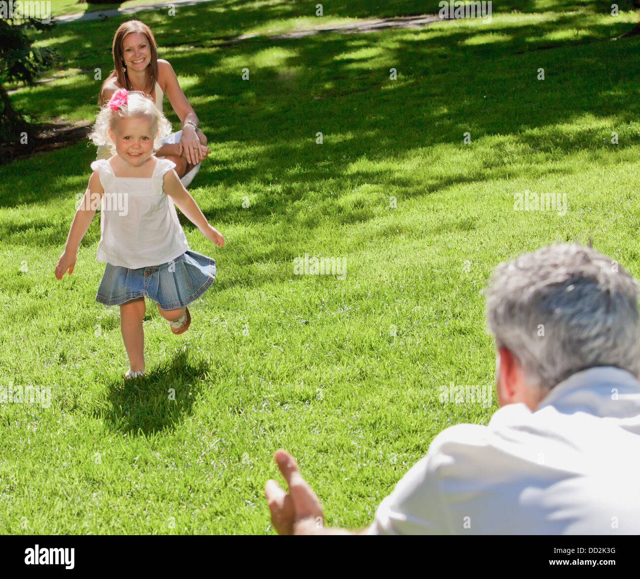 Young Girl Running To Her Father In A Park; Edmonton, Alberta, Canada Stock Photo