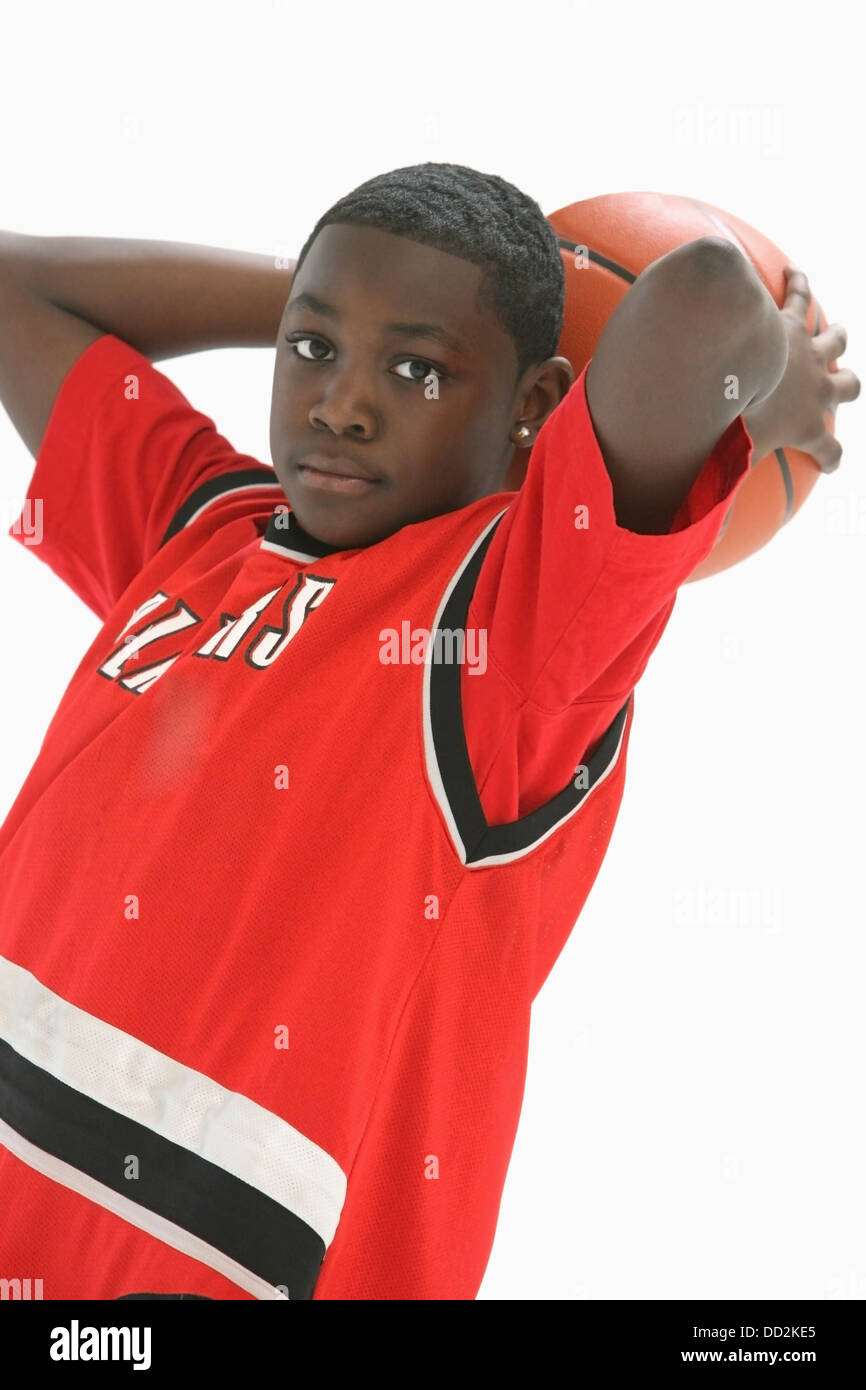 Teenage Boy In Red Jersey Holding Basketball Behind Head; Portland, Oregon, United States of America Stock Photo