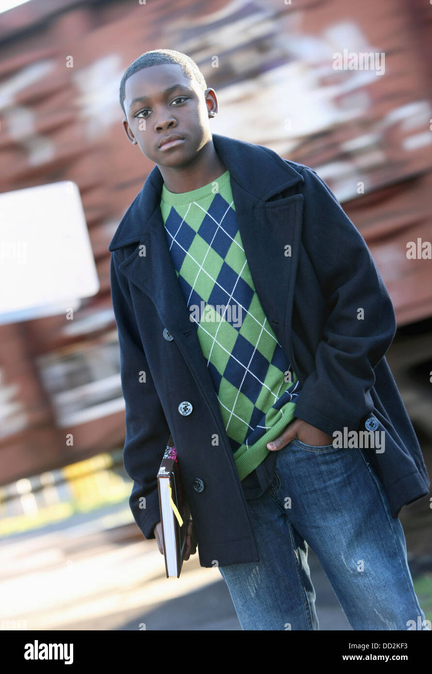 Teenage Boy Holding School Book Standing In Front Of Moving Train; Portland, Oregon, United States of America Stock Photo