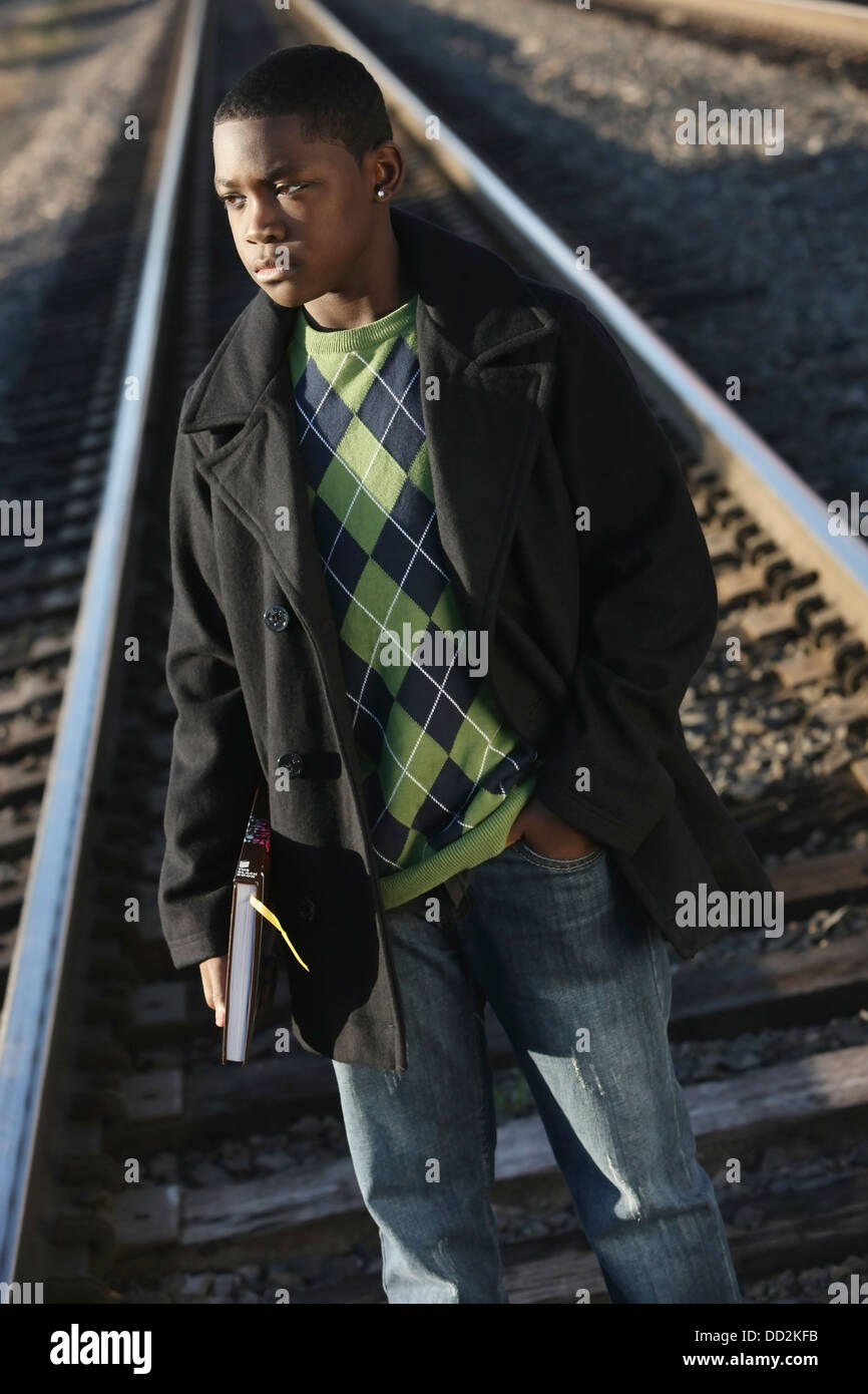 Teenage Boy Holding School Book Standing On Railroad Tracks; Portland, Oregon, United States of America Stock Photo