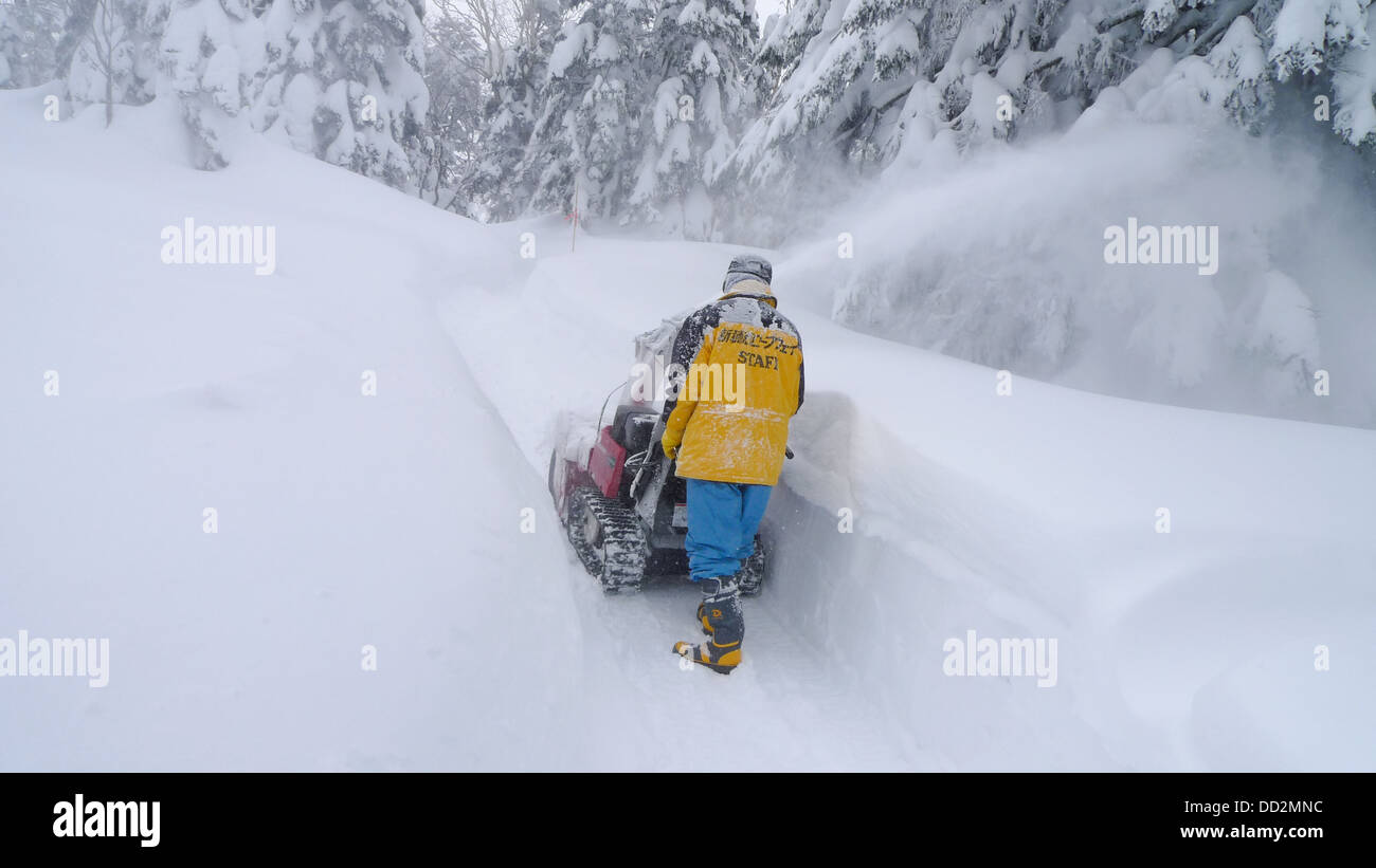 A man using a machine to clear snow. Stock Photo