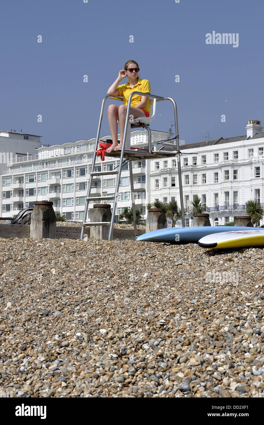 Female lifeguard on high seat on Eastbourne beach with two surfboards