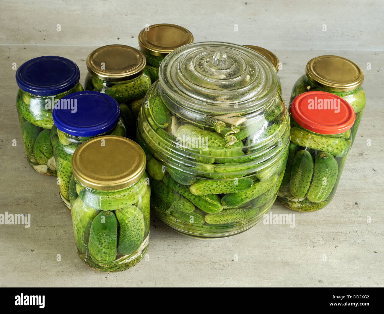 Pickled green cucumbers in glass jars on kitchen countertop Stock Photo